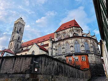Eine Kirche in Bamberg, zeigt gotische Elemente mit roten Dächern und detaillierten Fenstern. Der Turm erhebt sich majestätisch, eingerahmt von historischem Charme.