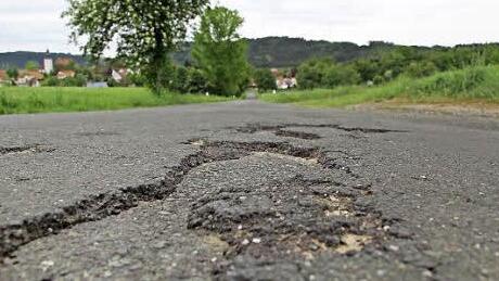 An vielen Stellen muss die Straße zwischen Feldbuch und Rugendorf (im Hintergrund) saniert werden, um noch größere Schäden zu vermeiden. Foto: Matthias Beetz
