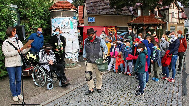 Zur Verlegung der Stolpersteine in Poppenlauer waren auch Schülerinnen und  Schüler der Grundschule mit Rektorin Simone Heinz an der Spitze gekommen  (rechts im Bild). In der Bildmitte der Künstler Gunter Demnig, im Rollstuhl  Klaus Bub. Ganz links Susanne Ziegler beim Verlesen der Biografie von  Thekla, Ilse und Kurt Heinemann vor dem Haus Hauptstraße 82. Foto: Dieter  Britz