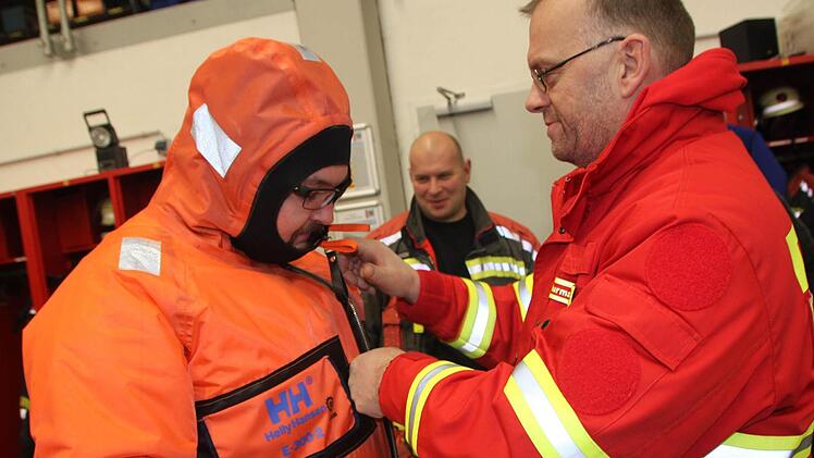 Stephan Murmann (rechts) erläutert den Überlebensanzug, in den Stephan Trapper von der Staffelsteiner Feuerwehr geschlüpft ist. Foto: Matthias Einwag