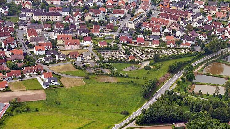 An der Einmündung des Lerchenwegs (rechts, bei den Weihern) soll ein Kreisverkehr gebaut werden. Von dort soll eine Straße zu den Einkaufsmärkten (ganz am linken Bildrand unten) führen. Die Aufnahme entstand vor Beginn der Erweiterungsarbeiten am Friedhof. Foto: Ronald Rinklef