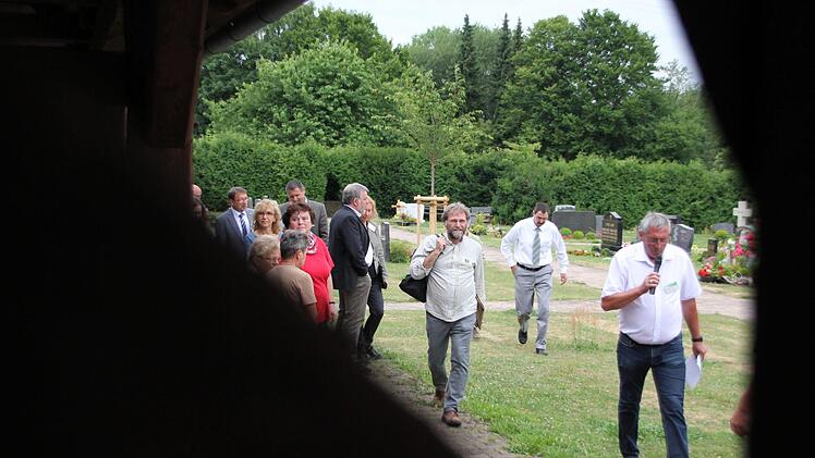 Vorneweg: Siegfried Burger, Vorsitzender der Dorfgemeinschaft Rügheim, führt Jurymitglieder und Dorfbewohner durch den Ort, hier beim Gang über den offen gestalteten Friedhof.