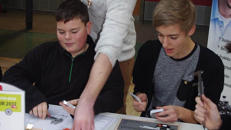Marco Weiß (Mitte) von der Firma Scherer & Trier erklärt Nico Remmert-Hartan (links) sowie Alexander Ketterer (rechts) den richtigen Umgang mit einem Messschieber.