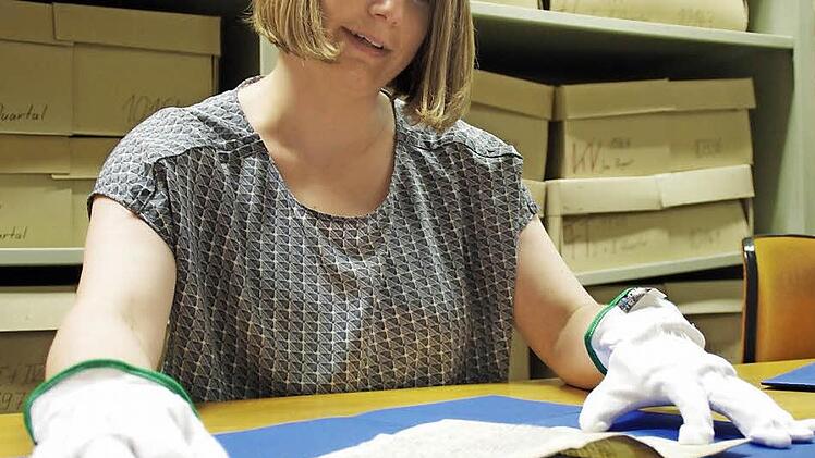 Über 600 Jahre alt ist dieses Pergament. Diese Frühmesse von 1381 ist eine der beiden ältesten Urkunden im Stadtarchiv. Das Schriftstück darf nur mit großer Vorsicht und Schutzhandschuhen berührt werden. Hinter Anja Weigelt türmen sich Kartons mit Zeitungen. Foto: Marco Meißner