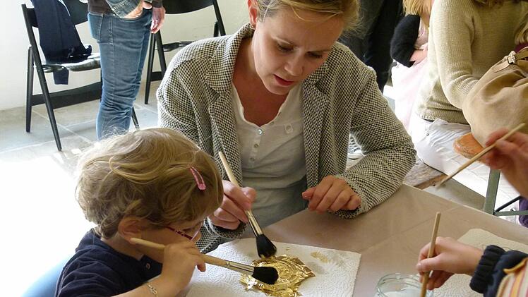 Vera Mamerow half ihrem Töchterchen Nora beim Basteln im Diözesanmuseum, eine Kaiserkrone zu vergolden.