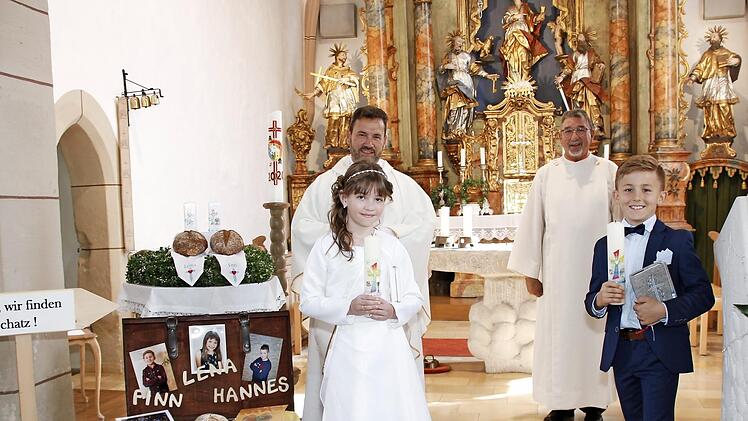 Lena Roos und Finn Kotschenreuther gingen in der Pfarrkirche St. Johannes der Evangelist zum ersten Mal zum Tisch des Herrn. Mit im Bild Pfarrvikar Anton Heinz (links) und Helmut Müller (Kirchenpfleger und Wortgottesdienstleiter).  Foto: K.- H. Hofmann