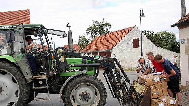 Wenn ein kleines Dorf feiert, helfen wie hier im Seßlacher Ortsteil Bischwind am Dienstag, Jung wie Alt mit. Bevor die nagelneuen Zelte auf der Festwiese hinter dem Feuerwehrhäuschen aufgebaut werden konnten, mussten die Pakete erst einmal dorthin transportiert und sortiert werden. Ortssprecher Udo Jahn (im roten T-Shirt) zeigte sich zuversichtlich, dass bis zum kommenden Sonntag alles bereit ist. Foto: Bettina Knauth