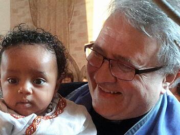 "Das ist eines meiner Lieblingsfotos", sagt Pfarrer Gerd Kirchner zu der Aufnahme, die den Geistlichen zusammen mit einem Flüchtlingskind nach dessen Taufe in der Friedenskirche zeigt.Rolf Pralle