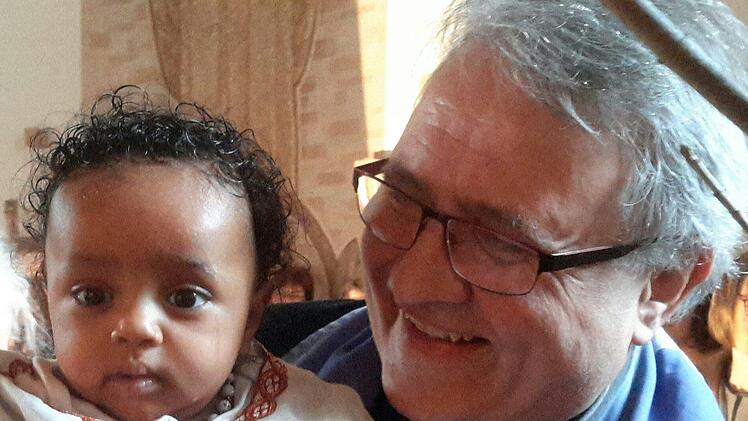 "Das ist eines meiner Lieblingsfotos", sagt Pfarrer Gerd Kirchner zu der Aufnahme, die den Geistlichen zusammen mit einem Flüchtlingskind nach dessen Taufe in der Friedenskirche zeigt.Rolf Pralle
