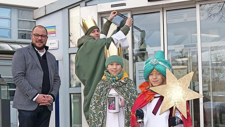 Sch&ouml;ner Start ins neue Jahr: Die Sternsinger Josias, Oscar und Ida bringen den Dreik&ouml;nigs-Segen am Eingang des Landratsamtes an. Links Landrat Sebastian Straubel.