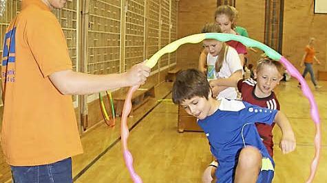 Christoph Ramming hält den Reifen - und die Kinder müssen als Raupe durch den Reifen klettern, ohne sich loszulassen. Foto: Sonny Adam