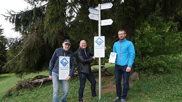 Bürgermeister Georg Seiffert (Mitte) probiert schon einmal aus, wie das neue Hinweisschild für Mountainbiker in der Natur wirkt. Mit ausgearbeitet und vorgestellt wurde das Schild von Manfred Reder vom RWV Haselbach (links) und Andi Rohe, Rhöntrail (rechts). Marion Eckert