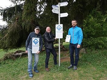 Bürgermeister Georg Seiffert (Mitte) probiert schon einmal aus, wie das neue Hinweisschild für Mountainbiker in der Natur wirkt. Mit ausgearbeitet und vorgestellt wurde das Schild von Manfred Reder vom RWV Haselbach (links) und Andi Rohe, Rhöntrail (rechts). Marion Eckert