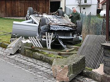 Das Unfallfahrzeug beschädigte in der Ortsmitte gegenüber des Kindergartens mehrere Zaunfelder und alte Sandstein-Pfosten, bevor es im Obstgarten auf dem Dach liegen blieb. Fotos: Ralf Ruppert