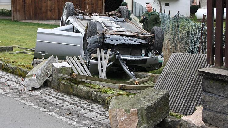 Das Unfallfahrzeug beschädigte in der Ortsmitte gegenüber des Kindergartens mehrere Zaunfelder und alte Sandstein-Pfosten, bevor es im Obstgarten auf dem Dach liegen blieb. Fotos: Ralf Ruppert