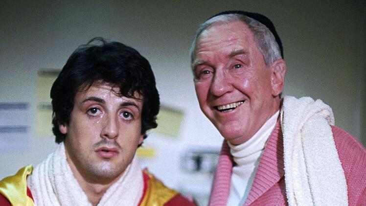 Der gro&szlig;e Tag ist gekommen: Trainer Mickey (Burgess Meredith, rechts) strotzt vor Optimismus, sein Sch&uuml;tzling Rocky (Sylvester Stallone) schaut noch etwas phlegmatisch aus der Boxerkluft.