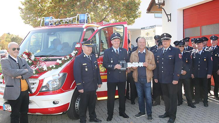 Neben dem mit Blumen geschmückten Fahrzeug übernimmt Kommandant Oliver Heland den Fahrzeugschlüssel aus den Händen von Oberbürgermeister Frank Rebhan. Jürgen W. Heike, Manfred Lorenz und Stadtbrandmeister Andreas Steller freuen sich anlässlich des feierlichen Moments. Foto: Michael Stelzner