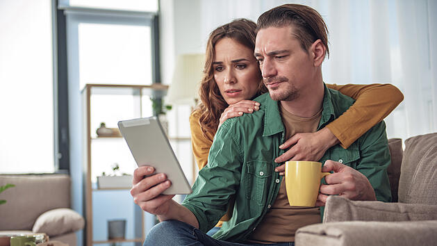 Junges Paar sitzt vor einem Laptob