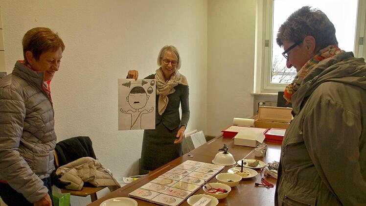 Irmgard Niederreiter (r.) zeigt Interessierten, wie sie sich die Installation ihrer Kunst vorstellt. Einbezogen sind hier die Kinder, die Selbstportraits gemalt haben. Foto: Susanne Deuerling
