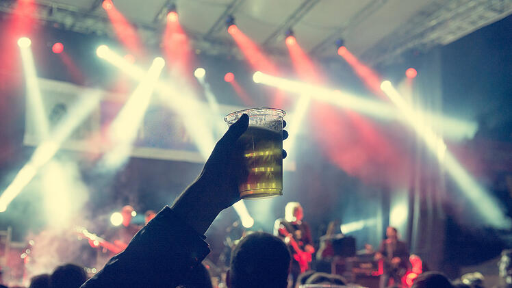Raised beer glass at a concert. Consuming alcohol at music event. WackenOpenAir Wacken2026 MetalFestival Bierpreis Festivalbier HeavyMetal Jubil&auml;um HolyGround Festivalgel&auml;nde Bechergr&ouml;&szlig;e Preissenkung MetalSzene Headliner Festivalstimmung Schleswig-Holstein Rockfans Openair Festivalbesucher Biertrinken Partystimmung Campingplatz JudasPriest DefLeppard Powerwolf Festivalkultur MetalFamily Infrastruktur Schlamm Festivalwiese ThomasJensen HolgerH&uuml;bner