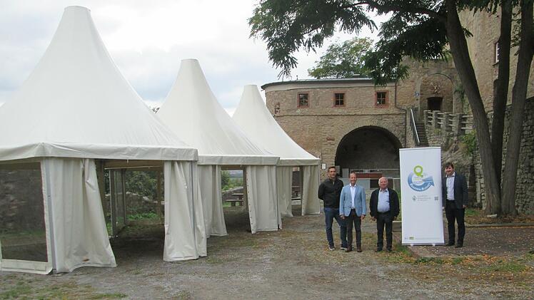 Auch bei unpassenden Wetterbedingungen können Besucher, dank der Pagoden-Zelte,  im Hof der Trimburg speisen und trinken. Die Einweihung ds Novums feierte (v.l.) Vorsitzender Micha Strauß, Bürgermeister Johannes Krumm, Burgführer Otmar Pfister und Allianz-Manager Holger Becker.  Foto: Winfried Ehling