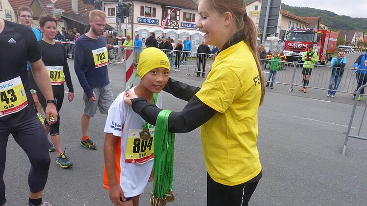 Alwin Purbojo freut sich über seine Medaille, die er nach dem Zieleinlauf erhält.