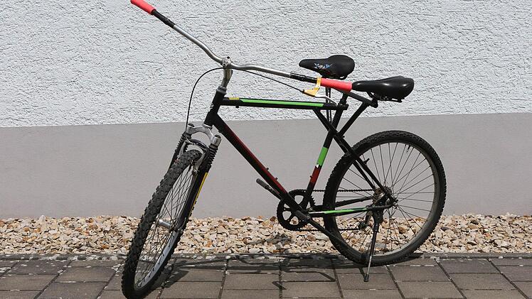 Auf dem "Tandem-Doppelsitzer" sitzen zwei Menschen auf einem Rad.