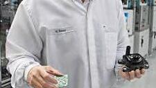 Werksleiter Hermann Bauer zeigt eine Platine, die in die elektronische Ölpumpe eingebaut wird.