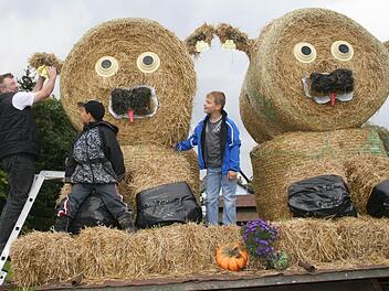 Wolfgang Goller (51) achtet auf jedes Detail: Deshalb müssen die beiden Strohkälbchen auf jeden Fall eine Ohrmarke mit Strichcode bekommen. Fritz Bodenschatz (7) und Christoph Goller (8) finden vor allem die roten Kälbchenschnuller lustig. "Das sind die Zungen", erklären sie. Fotos: Sonja Adam