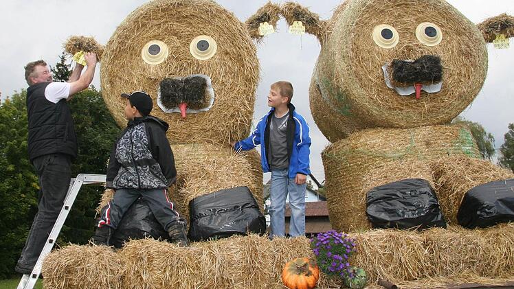 Wolfgang Goller (51) achtet auf jedes Detail: Deshalb müssen die beiden Strohkälbchen auf jeden Fall eine Ohrmarke mit Strichcode bekommen. Fritz Bodenschatz (7) und Christoph Goller (8) finden vor allem die roten Kälbchenschnuller lustig. "Das sind die Zungen", erklären sie. Fotos: Sonja Adam