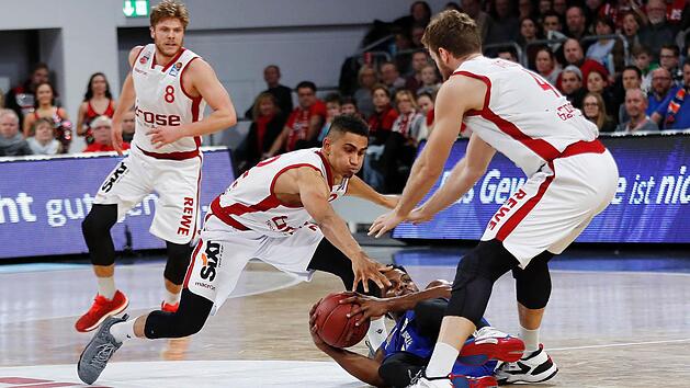 Maodo Lo und Nicolo Melli (r.) st&uuml;rzen sich auf den mit dem Ball am Boden liegenden Ex-Baunacher Marcos Knight; im Hintergrund beobachtet Lucca Staiger die Aktion seiner Mannschaftskollegen. Fotos: Daniel Lob