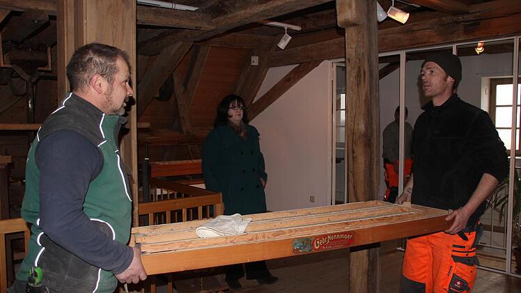 Sven Schneider (rechts) und Stefan Mützel tragen Teile aus dem Dachgeschoss nach unten. Das Ausräumen auf dem Dachboden erfolgt nach Absprache mit Projektleiterin Dr. Adina Rösch (im Hintergrund).