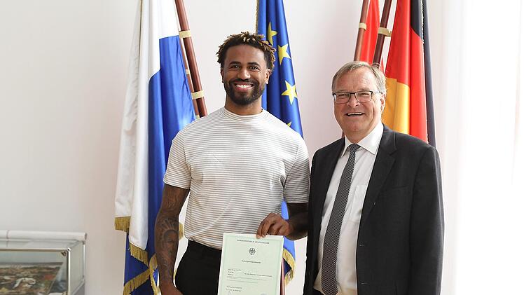 Stolz präsentiert Bryce Taylor (l.) seine Einbürgerungsurkunde, die er aus der Hand von Oberbürgermeister Andreas Starke erhalten hat. Foto: sportpress