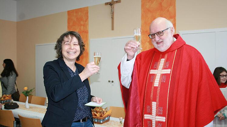 Pfarrgemeinderatsvorsitzende Regina Kirchner stößt mit Pfarrer Stephan Hartmann auf die Sebastianus Stube an, die jetzt in der neuen alten Schule eingeweiht wurde. Foto: Gabriele Sell