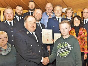 Per Handschlag nahm Kommandant Stefan Rupprecht Jan Feil als Feuerwehranwärter auf (Mitte). Dahinter: das neue Ehrenmitglied Rudolf Dorsch (Fünfter von rechts) und Alexander Marr (mit Urkunde), der für 25 Jahre aktiven Dienst geehrt wurde. Es gratulierten (von rechts) KBI Thilo Kraus, Bürgermeisterin Christine Frieß, Vorsitzende Sabrina Marr, Stadtrat Achim Ruß, Zweiter Vorsitzender Daniel Dorsch, stellvertretender Kommandant Dominik Dorsch, der Stellvertreter des Stadtkommandanten, Sven Völk...