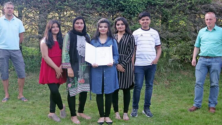 Remsha Ijaz (Mitte), umringt von ihren Geschwistern Rabia, Sundas und Usman sowie ihrer Mutter Robina, zeigt voller Stolz ihr Quali-Abschlusszeugnis. Klassleiter Marco Friedrich (links) und Bürgermeister Thomas Löffler (rechts) gratulierten ihr herzlich zu diesem tollen Ergebnis.