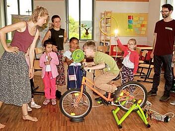 Mit eigener Muskelkraft erzeugten die Kinder Strom. Sie brachten auf dem Energiefahrrad eine Lampe zum Leuchten und einen Ventilator zum Drehen. Hier mit dem Team von der Energieagentur Unterfranken: Sa-raina Weigand, Amelie Scharrer und Fabian Onkels (von links).  Foto: gg
