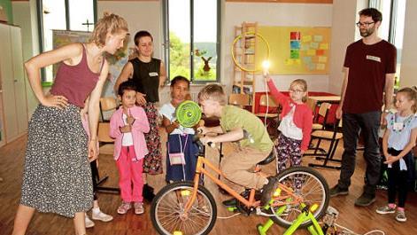 Mit eigener Muskelkraft erzeugten die Kinder Strom. Sie brachten auf dem Energiefahrrad eine Lampe zum Leuchten und einen Ventilator zum Drehen. Hier mit dem Team von der Energieagentur Unterfranken: Sa-raina Weigand, Amelie Scharrer und Fabian Onkels (von links).  Foto: gg