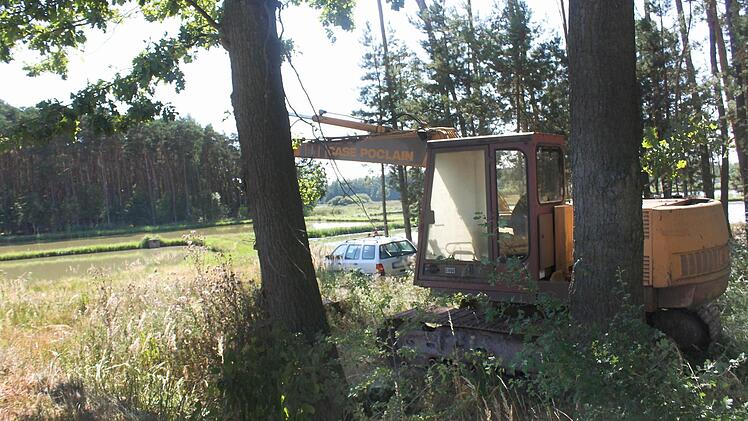 Dieser Bagger im Vordergrund und das Auto dahinter stehen seit Monaten in einem Wäldchen nahe einer Weiherkette bei Klebheim. Ein Fall für den ehrenamtlichen Naturschutzwächter. Fotos: Waltraud Enkert