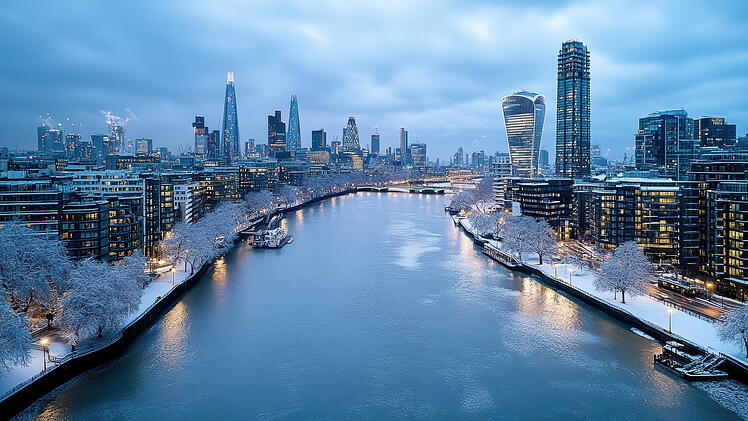Aerial cityscape view of London with snow covered banks, showcasing modern skyscrapers and river