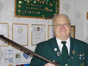 Michael Herbert mit einem Zimmerstutzen, den der Schützenverein während der Kriegswirren erfolgreich verstecken konnte. Mit der Traditionswaffe wurde das Königsschießen im Jubiläumsjahr ausgetragen. Im Hintergrund die zahlreichen sportlichen Auszeichnungen und Urkunden für Herberts ehrenamtliche Tätigkeit.Fotos: Stephanie Elm