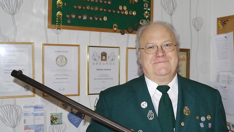 Michael Herbert mit einem Zimmerstutzen, den der Schützenverein während der Kriegswirren erfolgreich verstecken konnte. Mit der Traditionswaffe wurde das Königsschießen im Jubiläumsjahr ausgetragen. Im Hintergrund die zahlreichen sportlichen Auszeichnungen und Urkunden für Herberts ehrenamtliche Tätigkeit.Fotos: Stephanie Elm