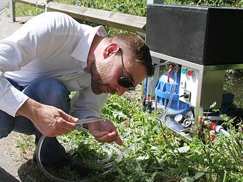 Diplom-Ingenieur Stefan Deegener von der Technischen Universität Hamburg-Harburg schließt probehalber die Wasserwaschmaschine in der Steinach an - und zeigt, wie sie normales Flusswasser in Trinkwasser verwandeln kann. Foto: Sonja Adam