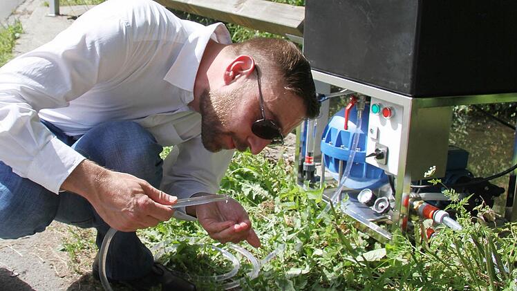 Diplom-Ingenieur Stefan Deegener von der Technischen Universität Hamburg-Harburg schließt probehalber die Wasserwaschmaschine in der Steinach an - und zeigt, wie sie normales Flusswasser in Trinkwasser verwandeln kann. Foto: Sonja Adam