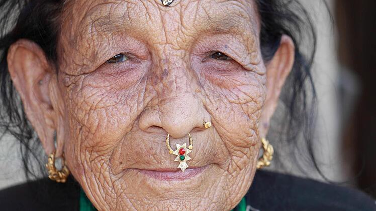 Das Gesicht einer alten Frau aus Nepal, die den typischen Schmuck des Landes trägt. Foto: Raimund Göhlich