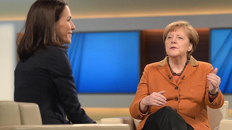 Bundeskanzlerin Angela Merkel (r, CDU) und die Moderatorin Anne Will unterhalten sich am 28.02.2016 in Berlin vor Beginn einer Sendung mit dem Thema "Debatte über Flüchtlingspolitik in Deutschland". Foto: Rainer Jensen/dpa