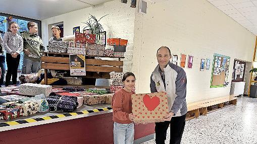 Eine Sch&uuml;lerin &uuml;bergibt ihr liebevoll verziertes P&auml;ckchen an Herrn Handel von &bdquo;Das kunterbunte Kinderzelt&ldquo;.