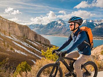 Mann f&auml;hrt E-Bike durch die Berge