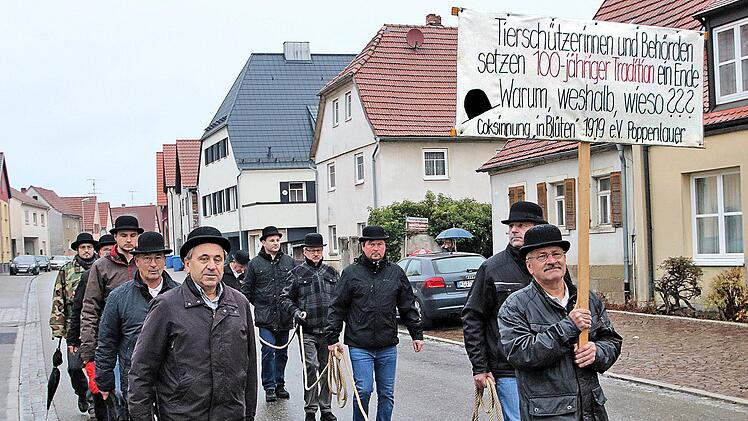 Ohne ein Schwein zogen die Mitglieder der Cocks-innung am Dienstagmorgen  durch Poppenlauer. Der leere Schweinekäfig war mit einer schwarzen Plane  bedeckt und erinnerte entfernt an einen Sarg. Foto: Dieter Britz
