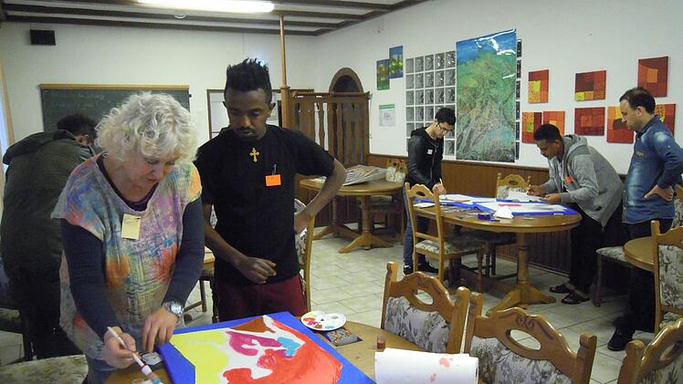 Helga Weißenberger zeigt einem jungen Flüchtling die richtige Maltechnik. Foto: Julia Raab